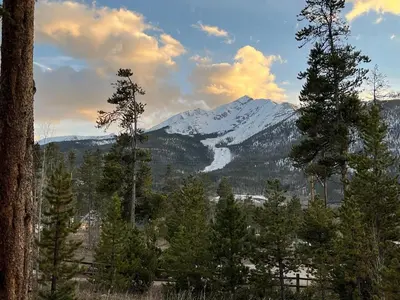 a snow covered mountain in the distance with trees at Waterdance House home in Frisco