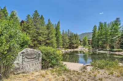 a stone bench next to a river with trees at Waterdance House home in Frisco