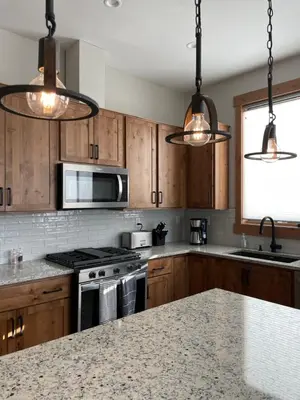 a kitchen with wooden cabinets and stainless steel appliances at Brand New! Private hot tub, bunk room and walkable to restaurants/shops in Fraser