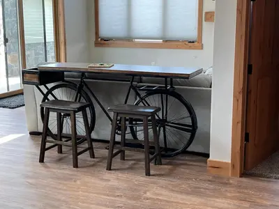 a wooden table with two stools and a bike at Brand New! Private hot tub, bunk room and walkable to restaurants/shops in Fraser