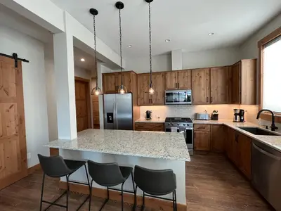 a kitchen with a large island with bar stools at Brand New! Private hot tub, bunk room and walkable to restaurants/shops in Fraser