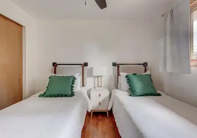 two beds in a white room with green pillows at Denver Hot Tub Retreat Near Downtown - 20 Percent Off Feb in Westminster