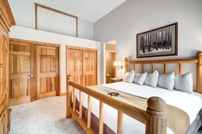 a bedroom with a wooden bed and wooden doors at Beautiful 5br Home at The Ranch - Kids Ski Free! condo in Keystone