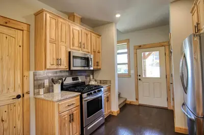 a kitchen with wooden cabinets and a stove and a refrigerator at Modern 3bd cabin in Edgewater in Granby