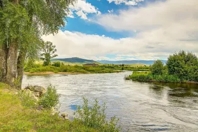 a river with grass and trees and a cloudy sky at Cozy 3 bedroom Mountain Getaway - Ski Fish Golf in Granby
