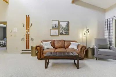 a living room with a brown couch and a chair at Cozy Winter Park Condo Bike, Ski, and Hike! in Winter Park