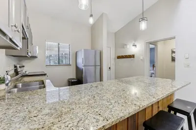 a kitchen with a granite counter top and a refrigerator at Cozy Winter Park Condo Bike, Ski, and Hike! in Winter Park