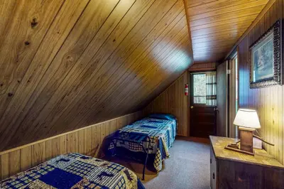 two beds in a room with wooden walls at Deck and Mtn Views! Family A-Frame Cabin in Bailey in Highland Park
