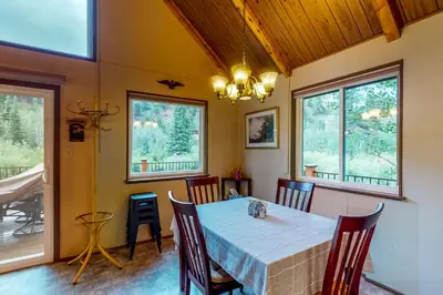 a dining room with a table and chairs and windows at Deck and Mtn Views! Family A-Frame Cabin in Bailey in Highland Park