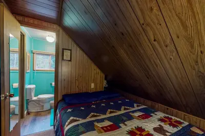 a bedroom with a bed with a wooden wall at Deck and Mtn Views! Family A-Frame Cabin in Bailey in Highland Park