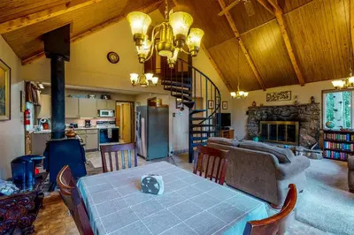 a living room with a table and a kitchen with a fireplace at Deck and Mtn Views! Family A-Frame Cabin in Bailey in Highland Park