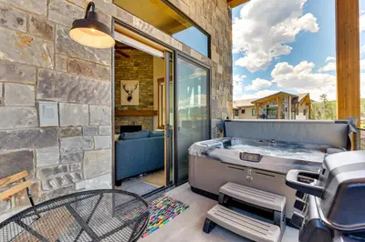 a hot tub on a patio with a stone wall at Mountain-View Fraser Condo with Balcony and Hot Tub! in Fraser