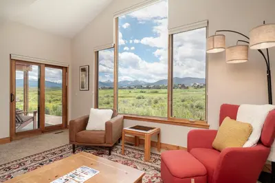 a living room with two chairs and a table and windows at 2002 Lupine Lane in Tabernash