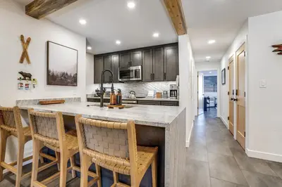 a kitchen with a large island with bar chairs at Family-Friendly Condo with Mtn Views in Keystone! in Keystone