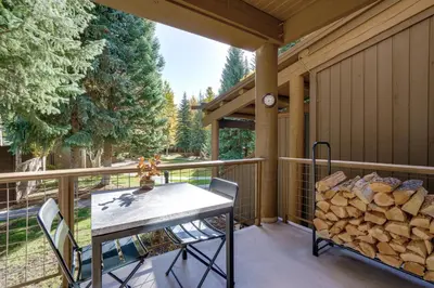 a porch with a table and chairs and a pile of logs at Family-Friendly Condo with Mtn Views in Keystone! in Keystone