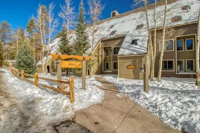 a house with a sign in the snow at Remodeled And Oversized 2-Bedroom Condo In West Keystone With Mountain Views, Pool, Hot Tub & Shuttle To Slopes! in Keystone