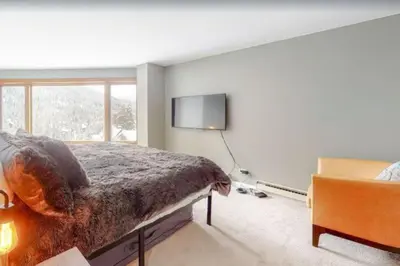 a bedroom with a bed and a flat screen tv at Renovated Condo In West Keystone With Balcony, Hot Tub, Pool & Free Shuttle To Slopes! in Keystone