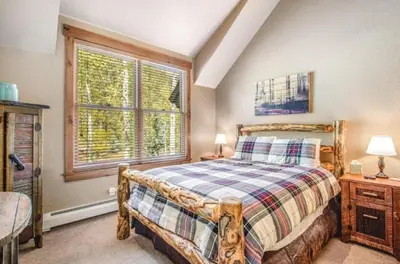 a bedroom with a wooden bed and a window at Lovely Townhome A Half-Mile From Keystone Gondola Wshared Hot-Tub & Excellent Views in Dillon
