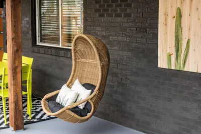 a wicker chair with pillows on a patio at Wild West Disco Haus 2! New Hot Tub, Patio + Gym in Denver