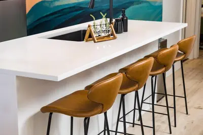 a kitchen with a white counter with four stools at Wild West Disco Haus 2! New Hot Tub, Patio + Gym in Denver