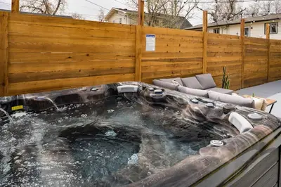 a hot tub in a backyard with a wooden fence at Wild West Disco Haus! New Hot Tub, Patio + Gym in Denver