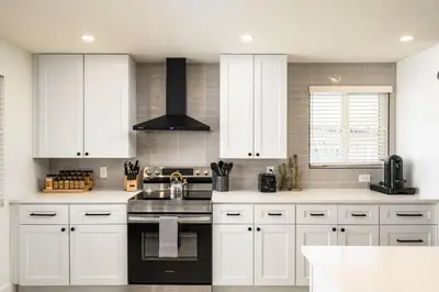 a kitchen with white cabinets and a stove top oven at Wild West Disco Haus! Sleeps 12, Hot Tub + Gym! in Denver