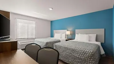 a hotel room with two beds and a television at WoodSpring Suites Greeley in Greeley