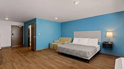a bedroom with blue walls and a bed and a chair at WoodSpring Suites Greeley in Greeley