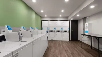 a room with white cabinets and a green wall at WoodSpring Suites Greeley in Greeley