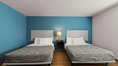 two beds in a room with blue walls at WoodSpring Suites Greeley in Greeley