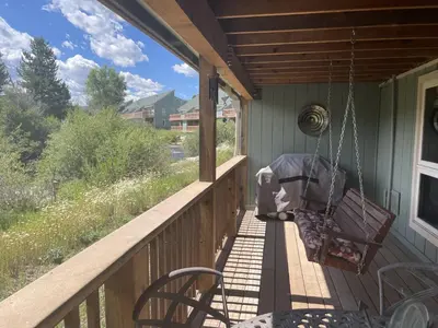 a porch with two chairs and a swing at Riverside Retreat in Funky Fraser on Train, Bike and Bus Routes in Fraser