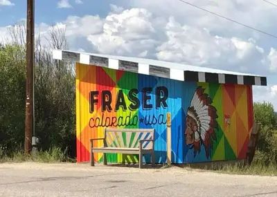 a bench sitting in front of a building with a mural at Riverside Retreat in Funky Fraser on Train, Bike and Bus Routes in Fraser