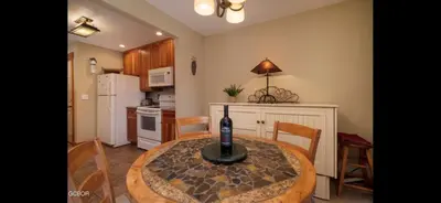 a kitchen with a table with a bottle of wine on it at Riverside Retreat in Funky Fraser on Train, Bike and Bus Routes in Fraser