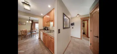 a kitchen with wooden cabinets and a dining room at Riverside Retreat in Funky Fraser on Train, Bike and Bus Routes in Fraser