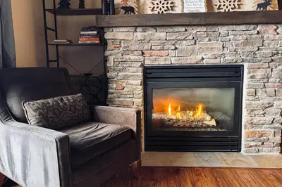 a living room with a stone fireplace with a chair at 310 Base Camp in Granby