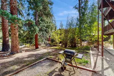 a grill in the middle of a yard with trees at On the Rapids - A Unit in Grand Lake