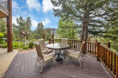 a patio with a table and chairs on a wooden deck at Alpine Suite - Minutes to RMNP, Hot Tub! in Estes Park