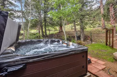 a hot tub with water in it in a yard at Alpine Suite - Minutes to RMNP, Hot Tub! in Estes Park