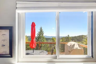 a window with a view of a deck with a red umbrella at The Tree House in Evergreen