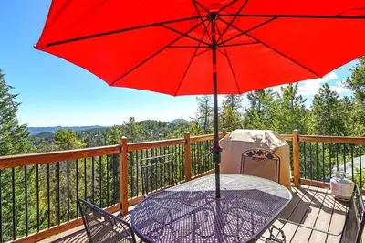 a table with a red umbrella on a deck at The Tree House in Evergreen
