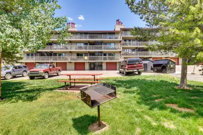 a picnic table and a grill in front of a building at Fraser Condo Rental with Balcony, Mountain Views! in Fraser