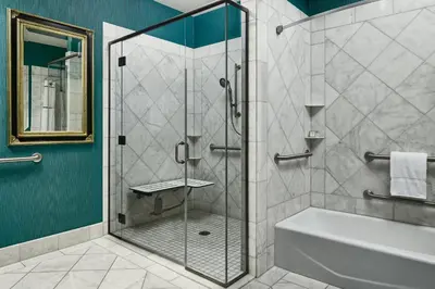 a bathroom with a glass shower with a tub and a sink at Woolley's Classic Suites in Aurora