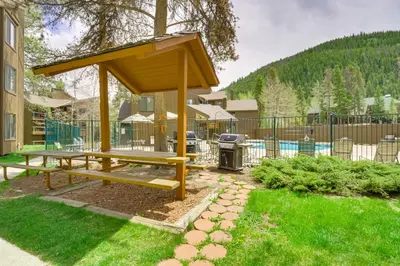 a wooden picnic table in a yard with a grill at Keystone Condo on Shuttle Line Less Than 1 Mi to Resort! in Dillon