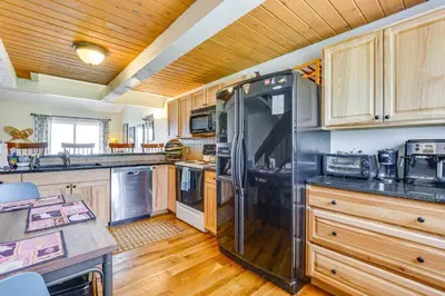 a kitchen with wooden cabinets and a black refrigerator at Family-Friendly Fraser Condo with Heated Pool Access in Fraser
