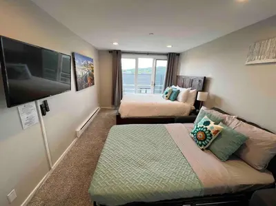a bedroom with two beds and a flat screen tv at Guest Suite Downtown Winter Park GREAT LOCATION in Winter Park