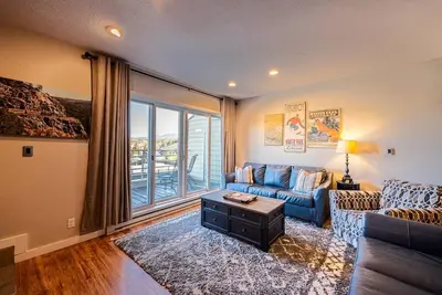a living room with a blue couch and a large window at Great Location! Downtown WP with Hot Tub! Sleeps 6! in Winter Park