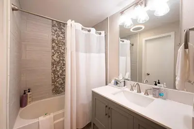 a bathroom with a sink and a tub and a mirror at Great Location! Downtown WP with Hot Tub! Sleeps 6! in Winter Park