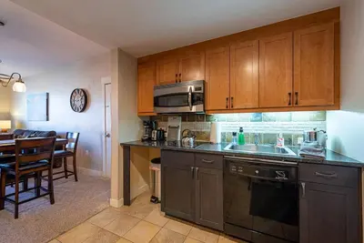 a kitchen with wooden cabinets and a dining room at Ski-In / Ski-Out 1 Bedroom Condo base of WP Resort in Winter Park