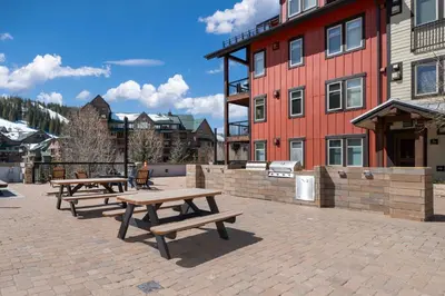 a group of picnic tables in front of a building at Ski-In / Ski-Out Studio Condo at the base of Winter Park in Winter Park