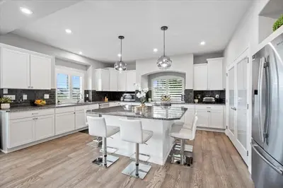 a kitchen with white cabinets and a large island with chairs at The Retreat at Buffalo Run Golf Course - Commerce City in Henderson